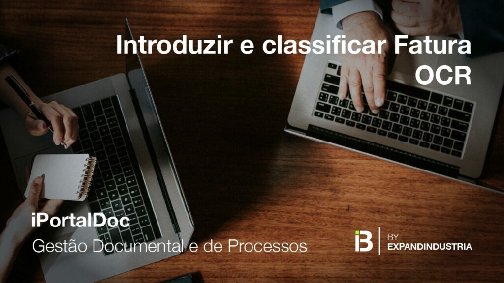 duas pessoas numa mesa de madeira com portáteis e uma delas esta a tirar apontamentos num bloco de notas